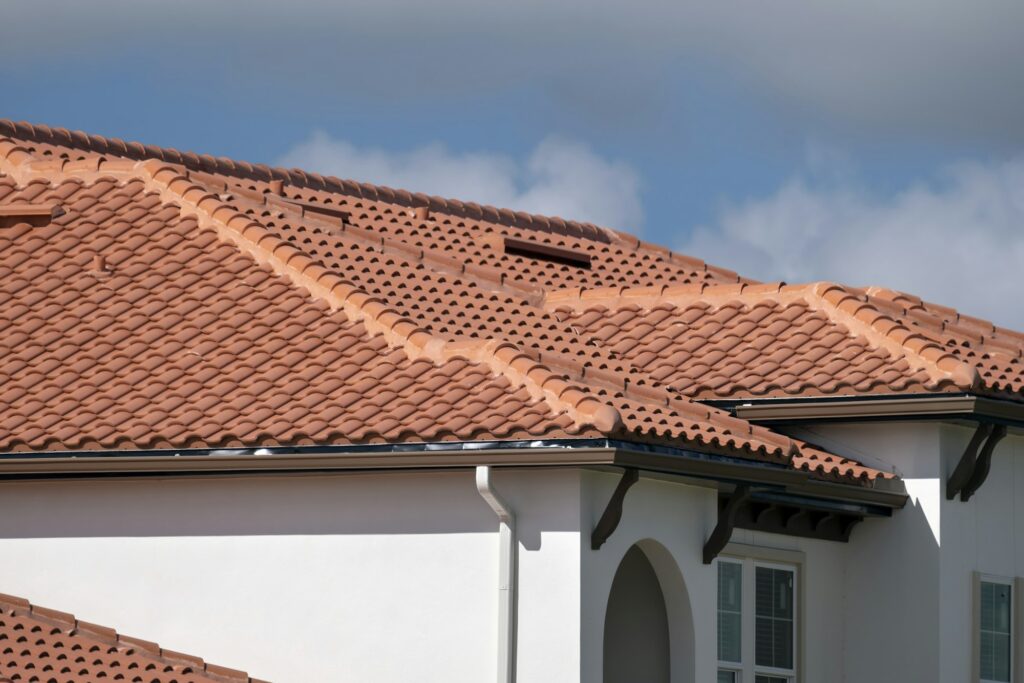 RM Roofing | overlapping rows of yellow ceramic roofing tiles covering residential building roof 1
