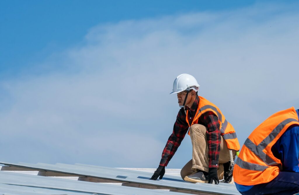 RM Roofing | roofer worker in protective uniform wear installing metal roof on top of the new roof